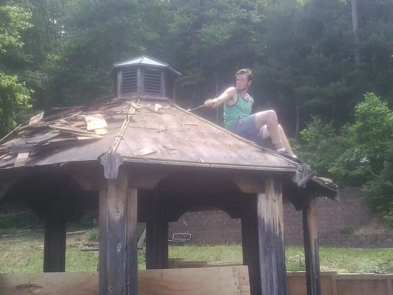 Tearing the old roof off a wooden gazebo before new shakes in Menasha