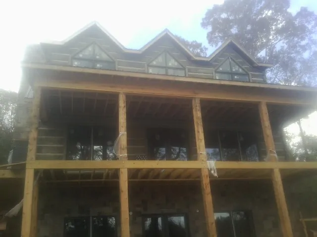 Dormers and porch framing on a large log home under construction — Roof Coating work by our crew in Menasha