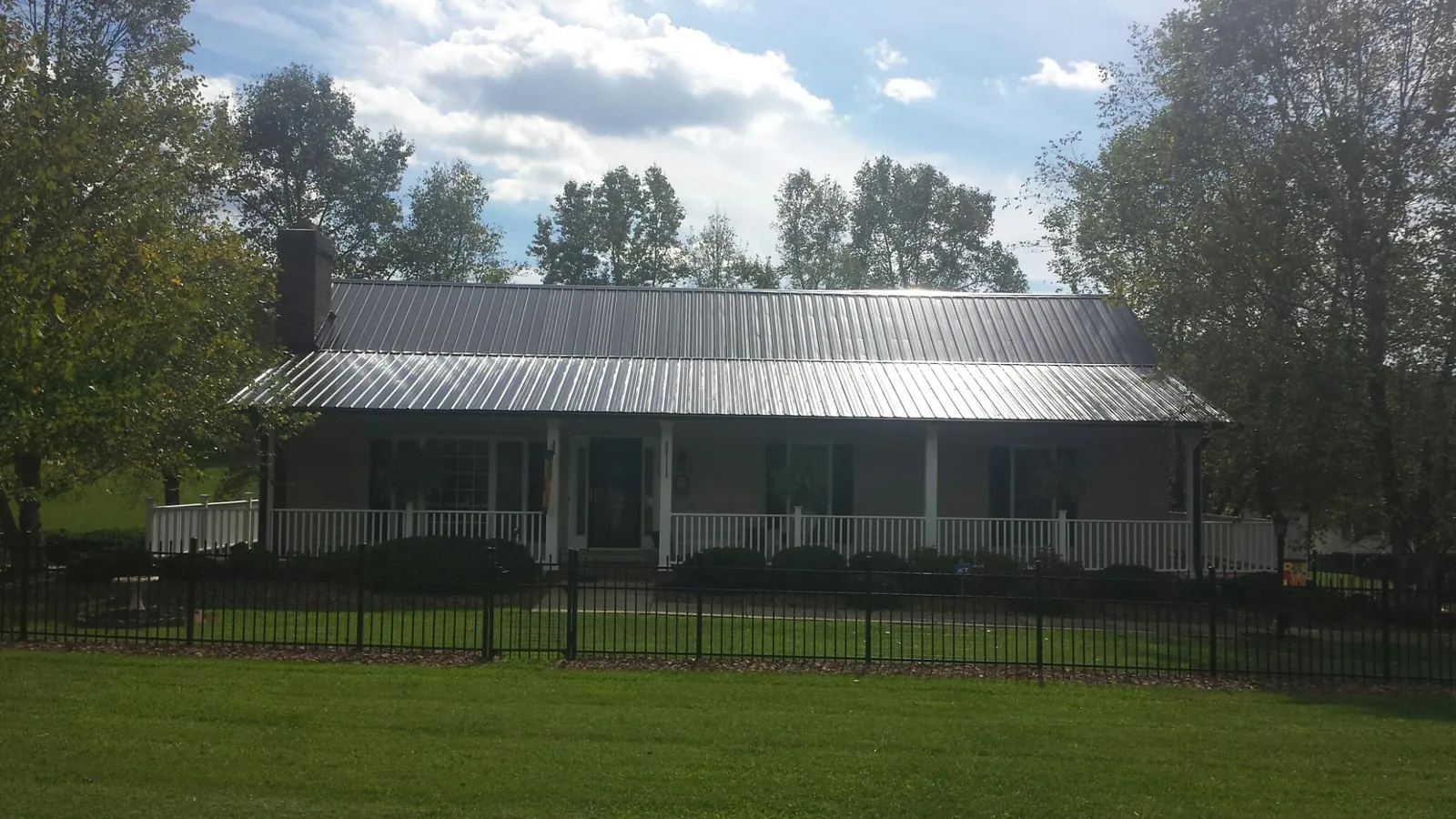 Gray metal roof on a brick ranch with a full width front porch — Gutter Guard Installation work by our crew in Menasha
